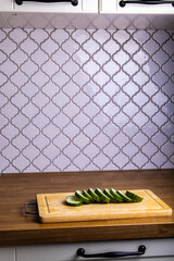 sliced cucumber lies on a wooden board on the background of the kitchen, isolated
