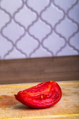 sliced tomato lies on a wooden plank on the background of the kitchen, isolated