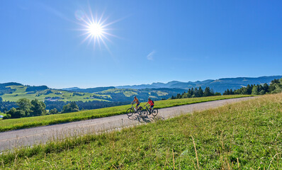 two senior girlfriends having fun during a cycling tour in the Allgau Alps near Oberstaufen, Bavaria, Germany - Powered by Adobe