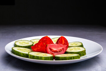 appetizing plate with sliced cucumbers and tomatoes on the background of the kitchen
