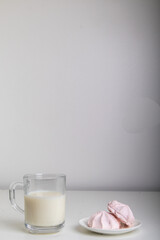 glass of milk and marshmallows on white background