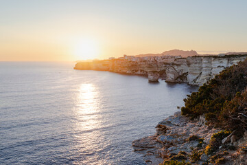 Coucher de soleil sur les falaises, la mer, et la citadelle de Bonifacio en Corse du Sud.