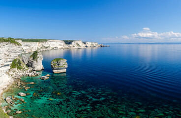 Vue sur les falaises de Bonifacio en Corse du sud. Les falaises blanches se reflètent sur la mer turquoise. Au fond on aperçoit les côtes de Sardaigne.