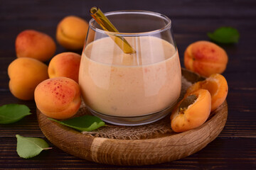Apricot smoothie in a glass on a dark wooden background.Close-up.
