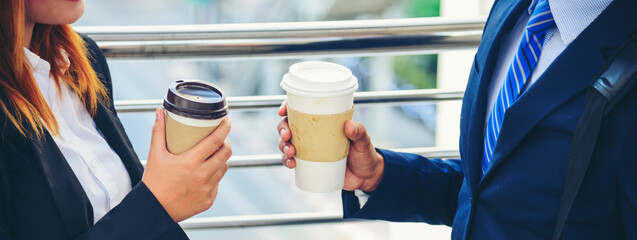 Banner Businessman Businesswoman drink coffee in town outside office modern city. Panoramic Hands holding take away coffee cup talking together happy. Copy Space Partner Business people cup of coffee