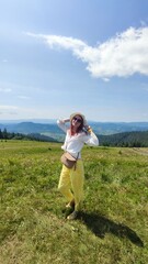 Traveling in summer Ukraine. Trip to Carpathian mountains. Woman tourist relaxing in flowers admiring view