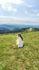 Fototapeta na wymiar Traveling in summer Ukraine. Trip to Carpathian mountains. Woman tourist relaxing in flowers admiring view
