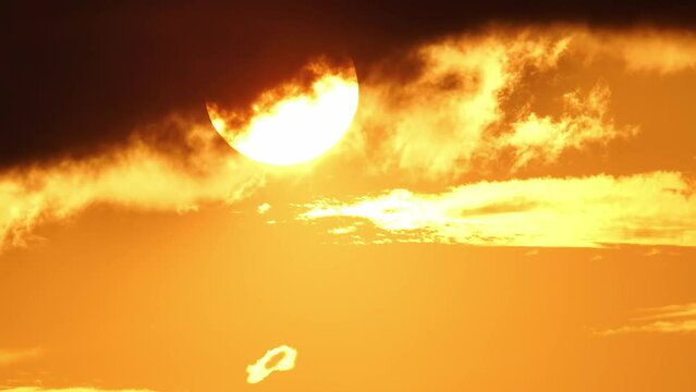 Cinematic sun set at red yellow and orange sky timelapse. Hot summer atmosphere at heat wave. Yellow sun setting at epic golden hour time lapse. Close up view of big round sun disk.