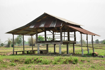 Bamboo hut with old galvanized metal roof. Country house in Asian style wagon. Rural countryside background, blue skies with clouds. Landscape with typical farm hut surround by terraced rice field