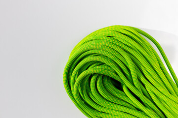 green rope for rock climbing and mountaineering lies on a white background. background image of...