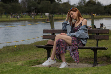 Teen young girl woman sitting on grass near lake,river, meditating,relaxing and smiling in simon bolivar Park in Bogota Colombia.inspiration nature beauty harmony landscape outdoors. - obrazy, fototapety, plakaty
