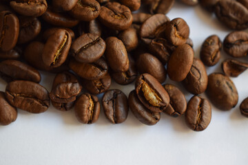 Fragrant roasted coffee beans closeup on a white textured background with copy space.