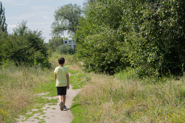 A boy walks along a path in a city park