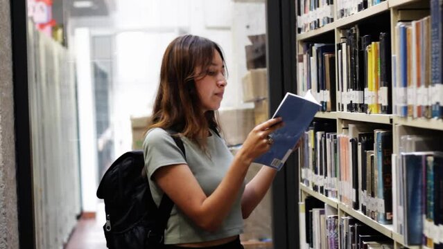 young student woman reading a book in a library at a university in colombia