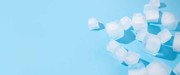 Many ice cubes on a blue background. Top view, flat lay. Banner
