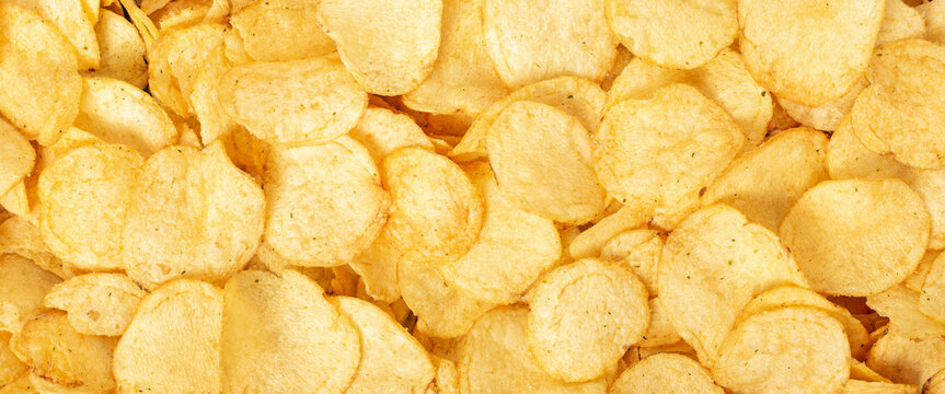 Crispy fresh potato chips, snacks background. Top view, flat lay. Banner.