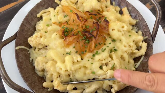 Eating Swabian noodles with cheese and onions, popular cheese spatzle