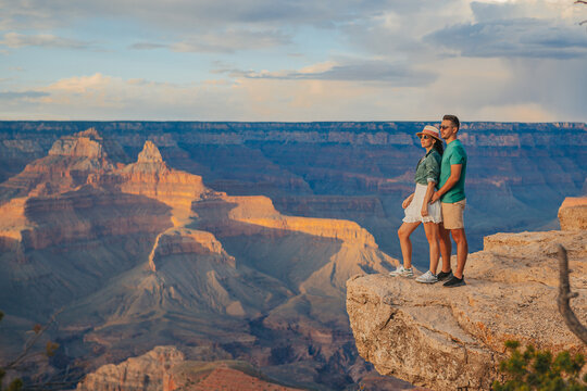 Happy couple on a steep cliff taking in the amazing view over famous Grand Canyon on a beautiful sunset, Grand Canyon National Park, Arizona, USA