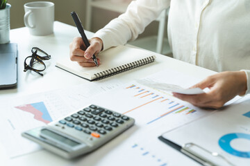 Women business people use calculators to calculate the company budget and income reports on the...