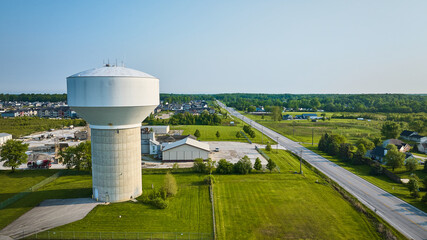 Rural area aerial nondescript white water tower with nearby housing