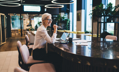 Positive female entrepreneur smiling while working in contemporary workspace