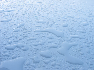 large and small water drops on a white plane, soft light, natural background after the rain
