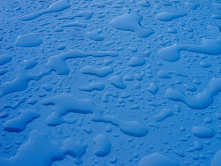large and small water drops on a white plane, soft light, natural background after rain
