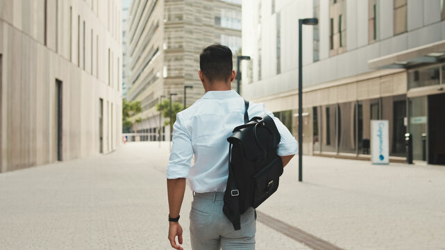 Young businessman walking through the business district, back view
