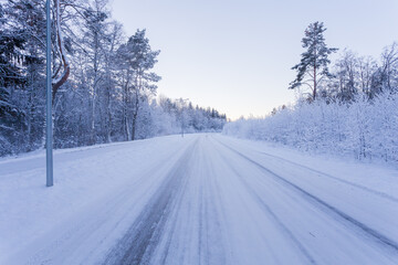 Winter evening forest with road covered with snow