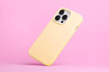 iPhone 15 Pro in yellow soft silicone case falls down back view, phone case mockup isolated on pink...