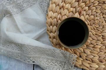 a cup of coffee on a straw woven napkin