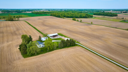 Aerial clean farmhouse landscape property aerial with green runoff ditches, paved road, empty fields © Nicholas J. Klein