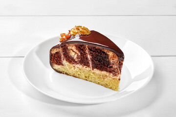 Slice of chocolate and vanilla sponge cake with ganache and caramelized walnuts