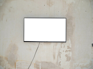 A wide white screen plasma TV in a black frame hangs on an old concrete wall. TV on a concrete wall.