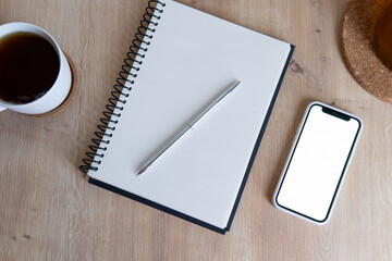 cup of coffee and phone and notebook on wooden table