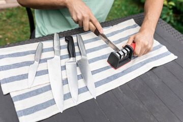 Close-up photo of man sharpening knives with special knife sharpener