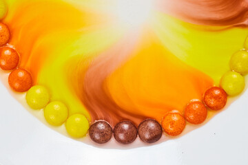 Water with color seeps into center of partial ring of colorful halloween candy