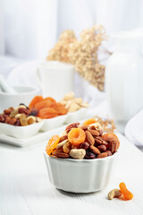 Dried fruits and assorted nuts on a white table.