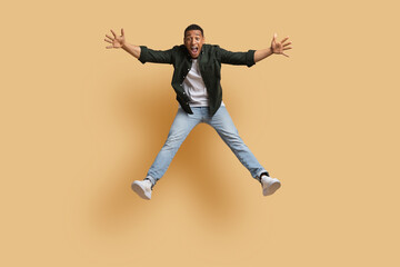 Fototapeta na wymiar Emotional thrilled young african guy jumping in the air
