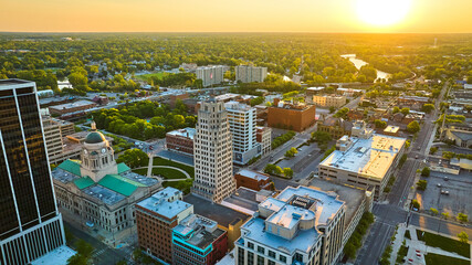 Aerial downtown summer sunrise Fort Wayne courthouse with river and skyscrapers green tree skyline