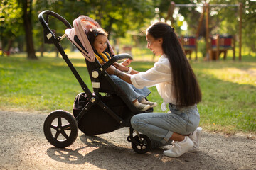 Fototapeta na wymiar Happy Korean Mom Playing With Baby In Stroller At Park