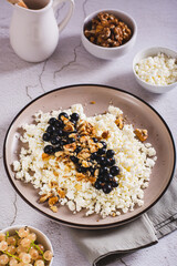 Homemade cottage cheese with fresh blackcurrants and walnuts on a plate vertical view