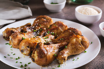 Spicy baked chicken drumsticks with green onions and sesame seeds on a plate