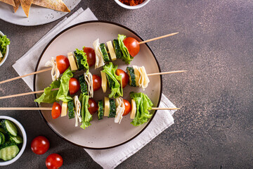 Snack on skewers of tomatoes, cucumber, cheese, pita bread and lettuce on a plate top view