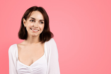 Cheerful millennial caucasian brunette woman looking at empty space, isolated on pink background