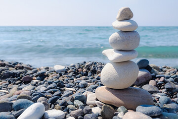 The stones are laid out in the form of a tower on the seashore. Light blue tones.