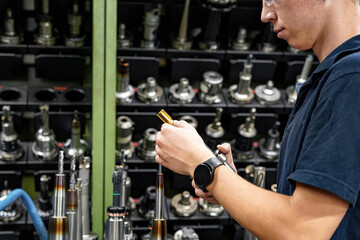 A worker in a tool warehouse inspects and selects cutters for work on a CNC milling and turning machine.