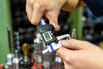 The worker measures the cutters with a caliper to work on milling and turning machines.