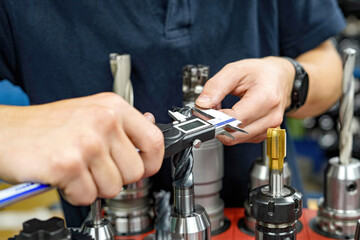 The worker operator of the cnc machine tool measures the cutting tool with a caliper for further...