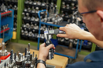 Measuring a cutting tool with a caliper for a CNC machine tool.